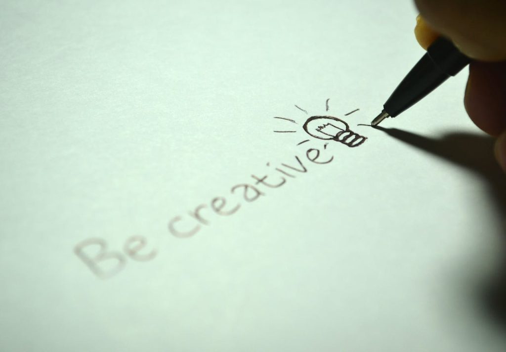 pexels photo 256514 Close-up of handwritten 'Be creative' with a light bulb sketch on paper.